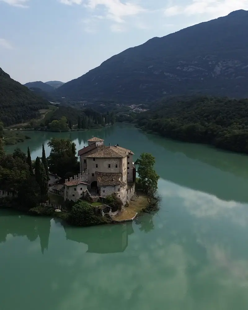 Castel Toblino on a narrow spit reaching into the green water of Lake Toblino