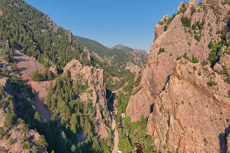 Red sandstone walls of Eldorado Canyon with pine slopes and the creek below