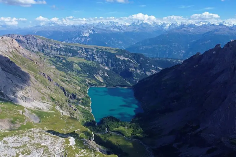 The turquoise reservoir of Lac de Tseuzier deep in its valley, with the Valais Alps ranged along the horizon