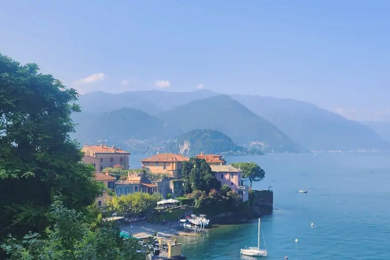 The village of Varenna stepping down its promontory to Lake Como, boats moored below and the far shore beyond