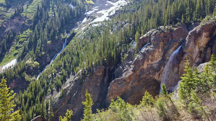 A waterfall dropping through cliffs above the Ironton forest, Colorado
