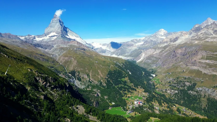 The Matterhorn above the Zermatt valley, its pyramid summit under a wisp of cloud