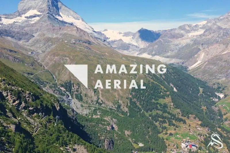 Aerial above the Zermatt valley with the Matterhorn rising beyond the green slopes and scattered hamlets