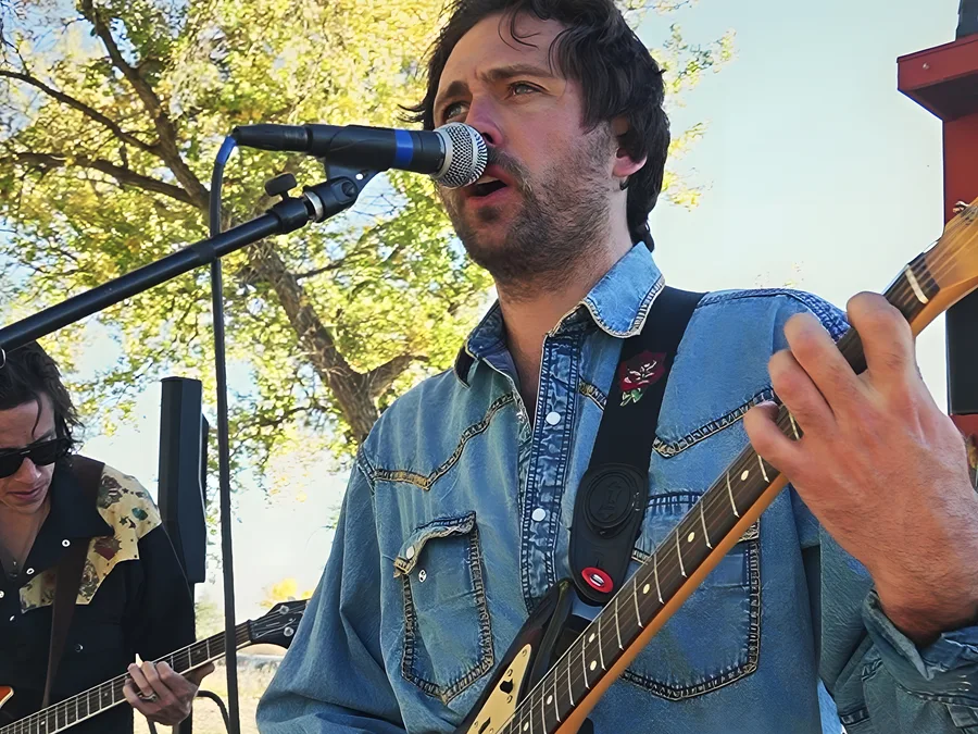 A band performing at golden hour at the 2023 Vybe festival, the singer backlit through fall leaves