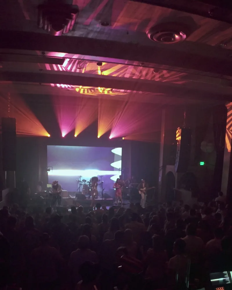 The stage at a Boogie Lights show glowing under a golden spotlight, viewed from the back of the room