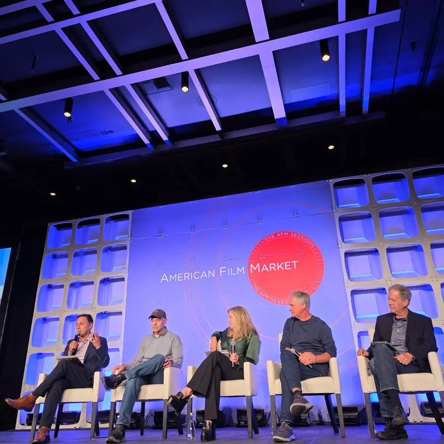 A moderator and five panelists seated across the AFM Sessions stage, notes in hand.