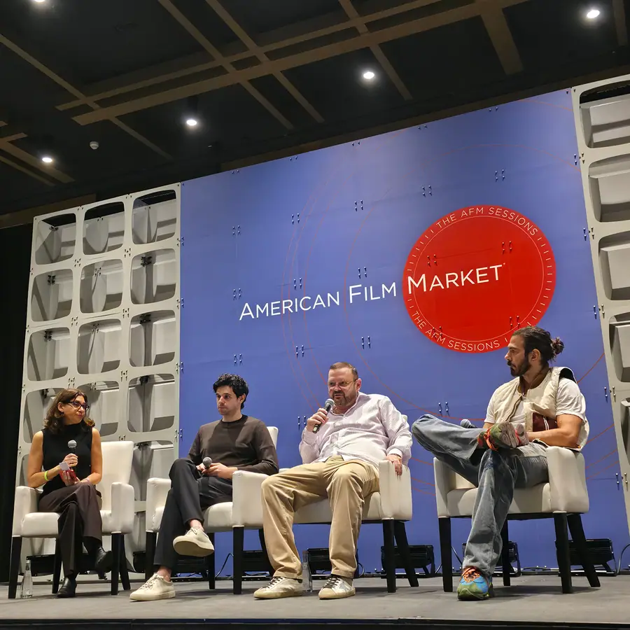 Four panelists on the AFM Sessions stage, one mid-answer with a microphone, the AFM Sessions red circle mark behind them.