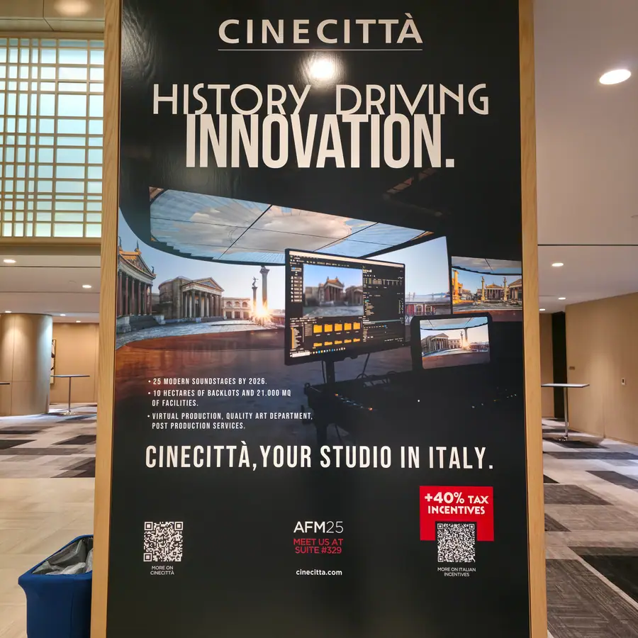 A trade-show banner for Cinecittà studios in Rome, advertising soundstages and an Italian production tax incentive, at an AFM exhibitor pavilion.