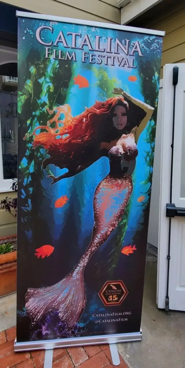 A full-height Catalina Film Festival roll-up banner on a brick porch: mermaid artwork in a kelp forest under the festival's title, the thirty-fifth-year mark and CatalinaFilm.org at its foot.