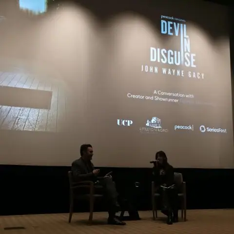 Two people seated in armchairs on a darkened stage, the screen behind them reading “Devil in Disguise: John Wayne Gacy — A Conversation with Creator and Showrunner,” with the UCP, Lifetime, Peacock and SeriesFest marks along the bottom.