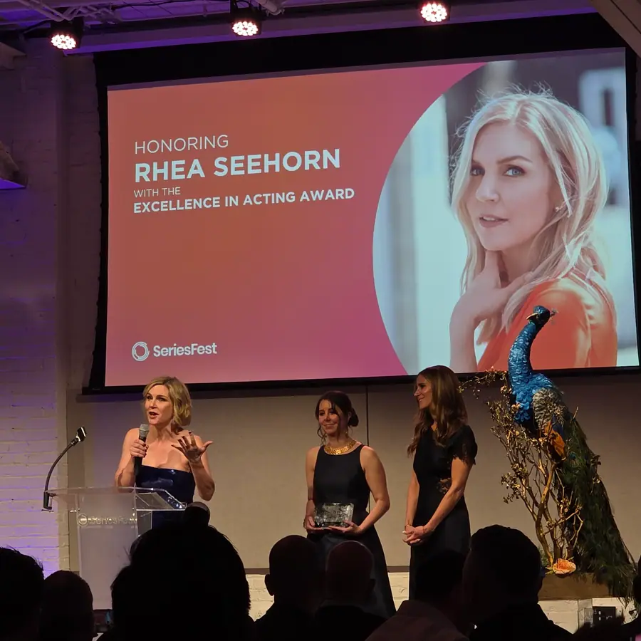 Three people at the Soirée podium under a screen reading “Honoring Rhea Seehorn with the Excellence in Acting Award.”