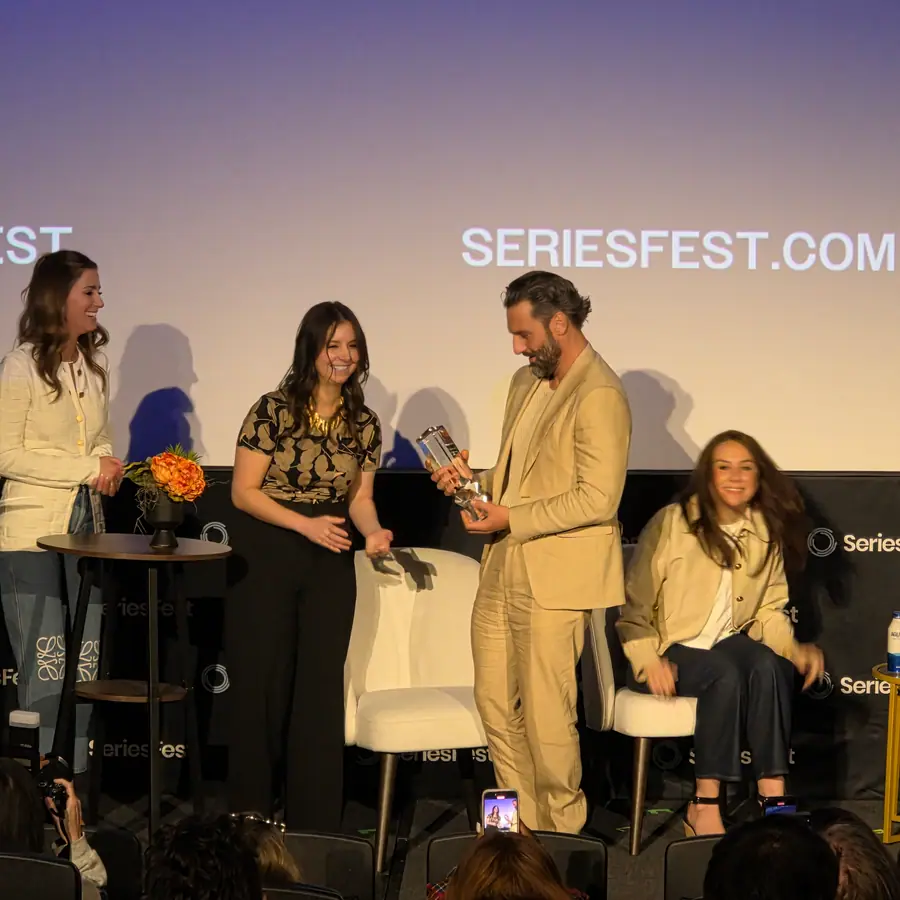Four people on stage handing over an award, the SeriesFest.com wordmark projected behind them.