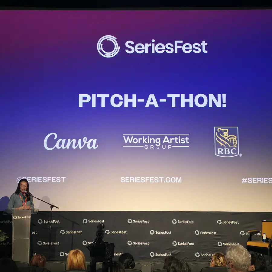 A host at the SeriesFest podium under a screen reading “Pitch-A-Thon!” with the Canva, Working Artist Group and RBC sponsor lockup.