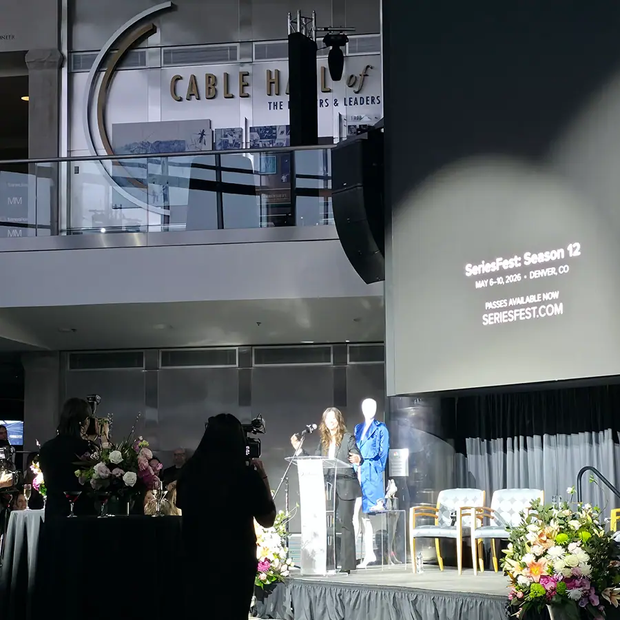 A host at the podium, a SeriesFest: Season 12 announcement lit up on the screen beside her.