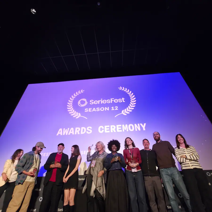 A lineup of Season 12 honorees on stage, the Awards Ceremony titlecard lit up behind them.
