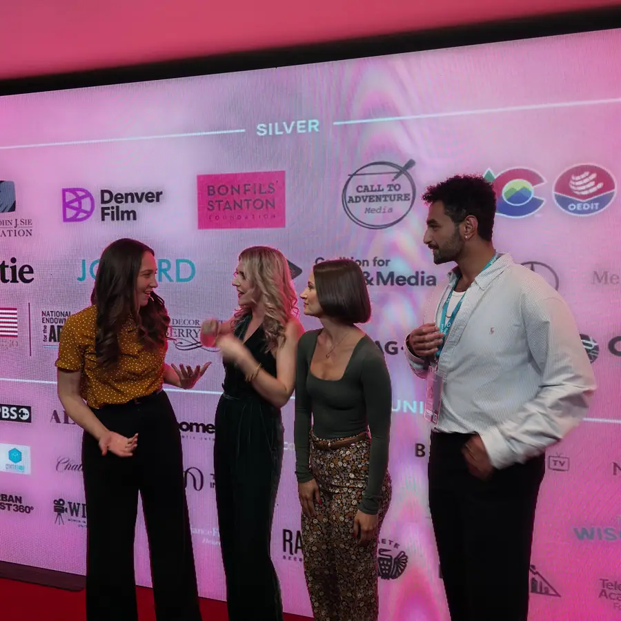 A small group talking in front of the SeriesFest 2026 sponsor wall on opening night.