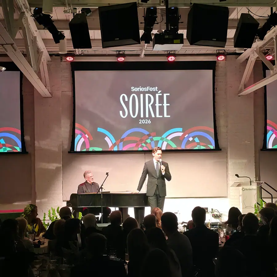 The Soirée stage under the 2026 titlecard, a host and pianist performing in front of the seated dinner crowd.